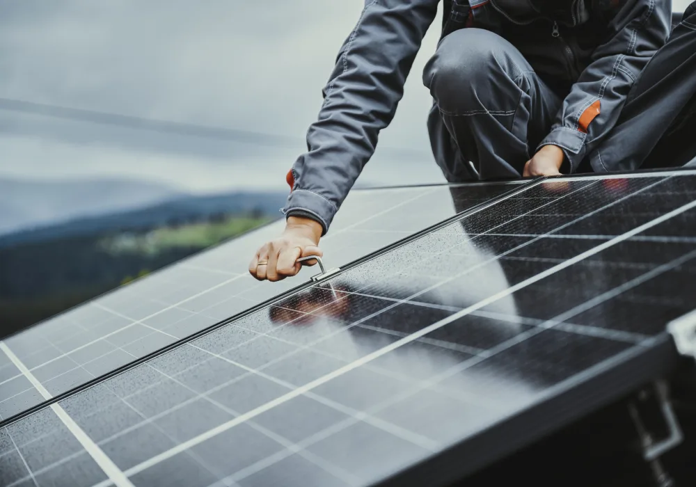 Ein Mitarbeiter montiert Solarpanels auf einem Hausdach