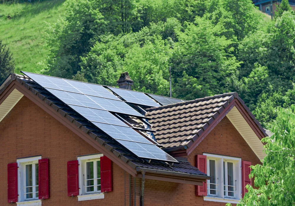 Solarpanels auf einem Hausdach. Das Haus hat rote Fensterläden und steht sinnbildlich für die verschiedenen Stromprodukte von ewl.