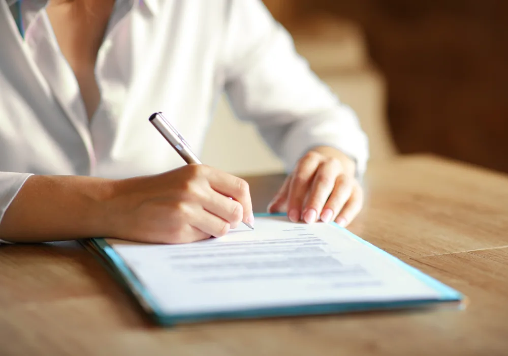 Eine Frau in weisser Bluse unterschreibt einen Vertrag für das PV Contracting.
