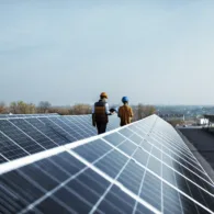 Blick auf das Dach einer grossen Überbauung. Zwei Experten begutachten die Solarpanels. Die Liegenschaft ist nach dem Prinzip Zusammenschluss zum Eigenverbrauch (ZEV) organisiert.