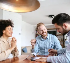 Ein Mitarbeiter von ewl führt eine Energieberatung mit einem Ehepaar durch. Die drei Personen sitzen in einer Wohnung am Tisch, die Stimmung ist professionell und fröhlich