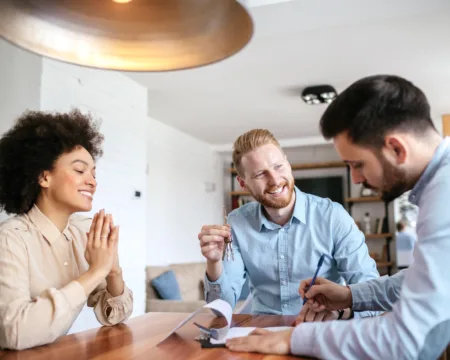 Ein Mitarbeiter von ewl führt eine Energieberatung mit einem Ehepaar durch. Die drei Personen sitzen in einer Wohnung am Tisch, die Stimmung ist professionell und fröhlich