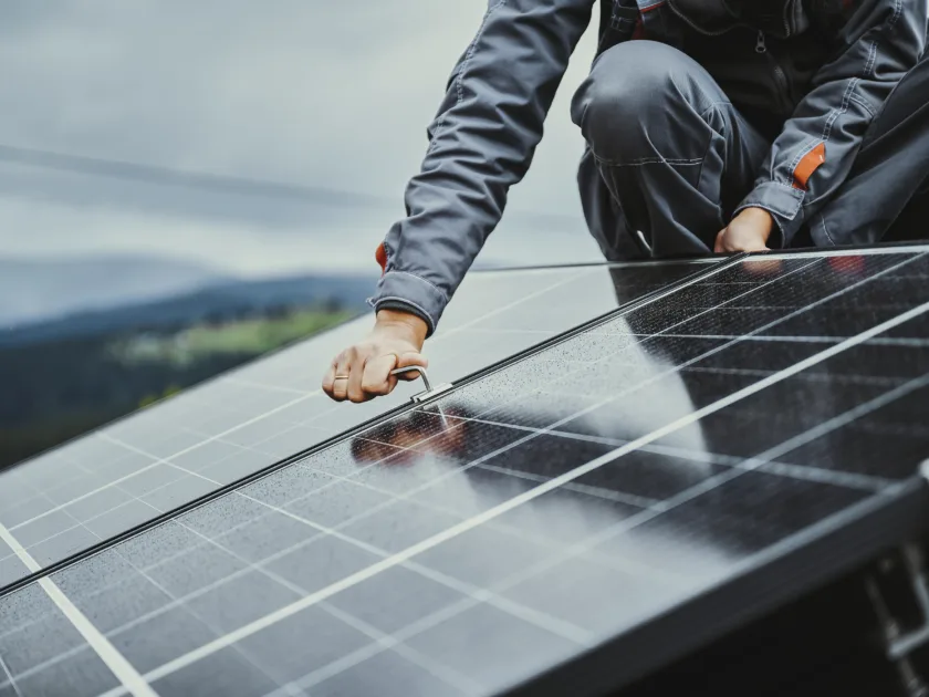 Ein Mitarbeiter montiert Solarpanels auf einem Hausdach
