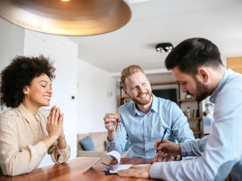 Ein Mitarbeiter von ewl führt eine Energieberatung mit einem Ehepaar durch. Die drei Personen sitzen in einer Wohnung am Tisch, die Stimmung ist professionell und fröhlich