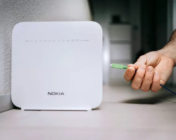 Glasfaser-Gateway von Nokia, eine Hand führt einen grünen Stecker an die entsprechende Buchse