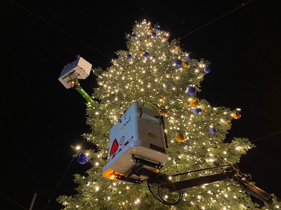 ewl Mitarbeiter beim Anbringen der Lichter und Kugeln am Weihnachtsbaum.